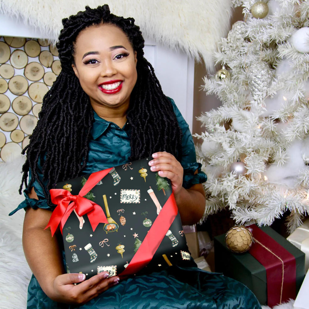 mahogany hold a gift box next to white holiday tree