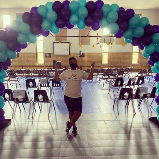 mahoney under blue and purple balloon arch inside auditorium 