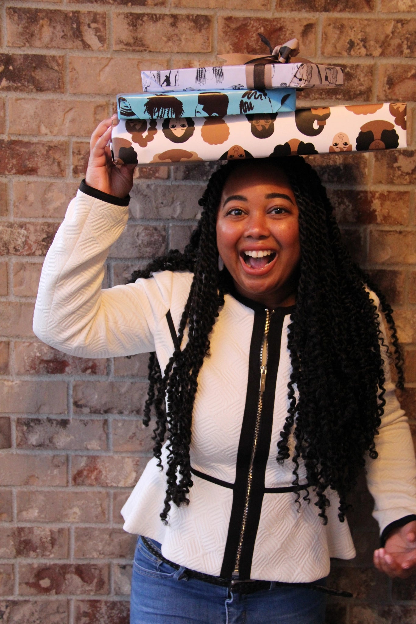 mahogany standing by brick wall with three gift boxes on her head